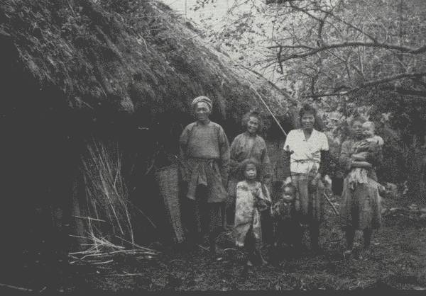 HAPPY FAMILY IN BACKWOODS

The Author spent two nights in this crudely-thatched home in the hills.
Though poor, the people were extremely hospitable—and invariably happy.