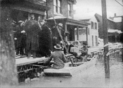 Rescuer leaving one of the houses in the flooded district and removing a family to safety