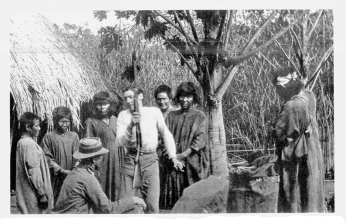 Fig. 22—Trading with Machiganga Indians in a reed swamp
at Santao Anato, Urubamba Valley, before Rosalina. Just outside the
picture on the right is a platform on which corn is stored for
protection against rodents and mildew. On the left is the corner of a
grass-thatched cane hut.